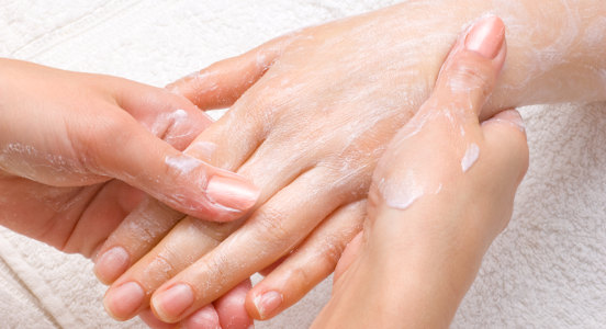 applying peeling scrub or moisturizing cream onto the hands
